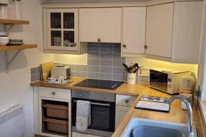a kitchen with white cabinets and a counter top at Fossil Cottage (Berryl Farm Cottages) in Whitwell