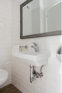 W białej łazience znajduje się umywalka i lustro. w obiekcie Casaletto's Suites w mieście Riano