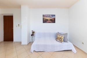 a white bedroom with a white bed with a picture on the wall at Apartments Seaside in Bibinje