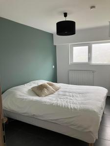 um quarto com uma cama branca e uma almofada em Le beau petit bosquet em Hotton