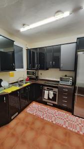 cocina con armarios negros, fregadero y microondas en Habitación en centro de Barcelona, en Barcelona