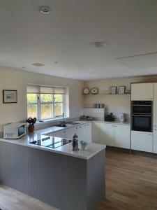 a large kitchen with white cabinets and appliances at Bandar Cottage, farm cottage, close to Narberth, Pembrokeshire in Narberth