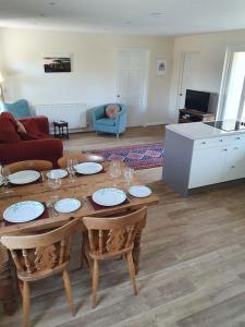 a living room with a wooden table with plates and chairs at Bandar Cottage, farm cottage, close to Narberth, Pembrokeshire in Narberth