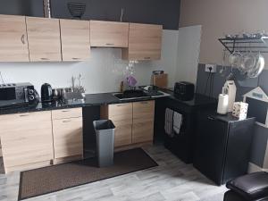 a kitchen with wooden cabinets and a black counter top at Llandudno Beachfront 2 Double Bedroom Apartment 2nd Floor in Llandudno
