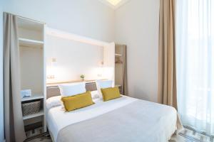 1 dormitorio con 1 cama blanca grande con almohadas amarillas en Feelathome Casa Bertrand, en Barcelona