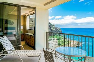 balcón con mesa, sillas y vistas al océano en Hawaiian Princess Makaha, en Waianae