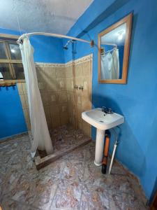 a blue bathroom with a sink and a shower at Mayan Casas in San Marcos La Laguna