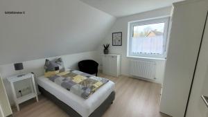 a white bedroom with a bed and a window at Ferienwohnung 2 - "Ferienhaus Seibert" in Ellerdorf