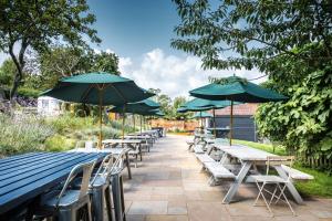 a row of tables and chairs with umbrellas at The Ship At Dunwich in Dunwich