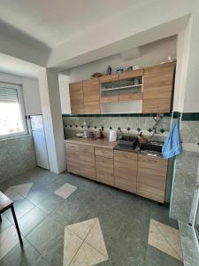 a kitchen with wooden cabinets and a tile floor at Viktorija's Apartment in Gevgelija