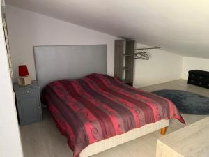 um quarto com uma cama grande e um cobertor vermelho em L appart d Ange 2 idealement situe 47m2 entre le port et le village em Gruissan