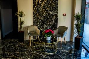 un vestíbulo con 2 sillas y una mesa con flores en Sonio Boutique Hotel en Mamaia