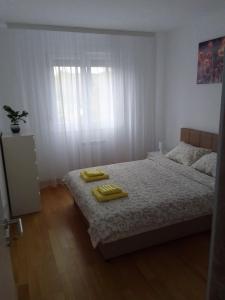 a bedroom with a bed with two yellow towels on it at Happy Day in Obrenovac