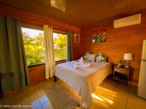 1 dormitorio con 1 cama en una habitación con ventana en Bungalows Yakari Grei, en San Ramón