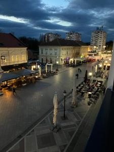 una plaza de la ciudad por la noche con gente y edificios en Apartman Loft 72, en Slavonski Brod