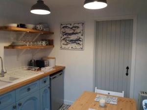une cuisine avec des placards bleus et une table en bois dans l'établissement The Bake House (Berryl Farm Cottages), à Whitwell