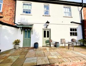 a patio in front of a white house with a green door at The One @ West End in West Haddon