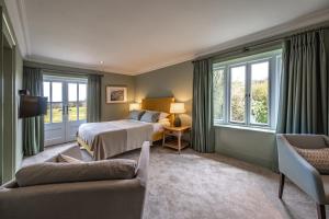 a bedroom with a bed and a couch and windows at The Crown Inn in Stoke-by-Nayland