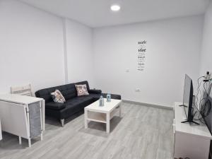salon z czarną kanapą i stołem w obiekcie Apartamento mi currilla w mieście Sanlúcar de Barrameda