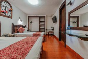 梅里達的住宿－Hotel Maya Yucatan，酒店客房设有两张床和墙上的时钟。
