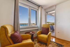 a living room with two chairs and a table and windows at Studio Apartment Harbour Pula in Pula