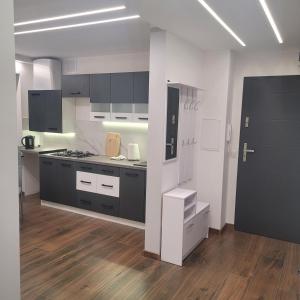 a kitchen with black and white appliances and wooden floors at Mieszkanie centrum in Lidzbark Warmiński