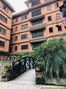 a building with a bridge and plants in front of it at Courtyard Pujan Hotel in Kathmandu
