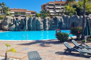 - une piscine avec 2 chaises et un mur de roche dans l'établissement Jardín del Teide, à Puerto de la Cruz