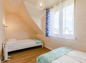 a attic room with two beds and a window at DOMKI SUL MARE in Dębki