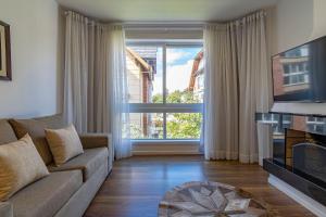 een woonkamer met een bank en een groot raam bij Rosa Edifício English Place in Gramado