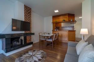 een woonkamer met een bank en een tafel met een open haard bij Rosa Edifício English Place in Gramado