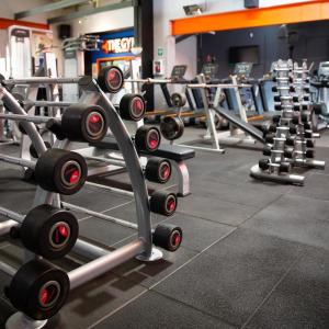 a gym with several rows of squat racks with weights at CCULB Resort & Convention Hall in Gazipur