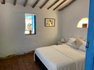 a bedroom with a white bed and a window at Casa de la Piedra in Barichara