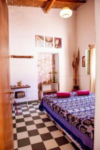 a bedroom with a bed and a checkered floor at Apapacho Hostel in Tilcara
