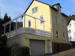 uma casa amarela com uma cerca branca e uma garagem em Ferienhaus Villa Rosi em Cochem