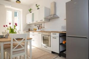 a white kitchen with a table and a refrigerator at BRAND NEW City Center Apartment Nostalgija in Split