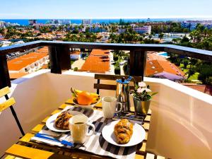 une table avec des assiettes de nourriture sur un balcon dans l'établissement Blue Ocean Holiday Home, à Playa del Ingles