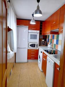 a kitchen with wooden cabinets and white appliances at Mi rincón de Rota in Rota