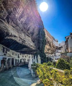 eine Gruppe von Sonnenschirmen und Stühlen neben einem Berg in der Unterkunft Casa Cueva La Luna in Setenil de las Bodegas