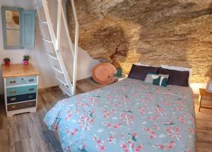 ein Schlafzimmer mit einem Bett vor einer Steinmauer in der Unterkunft Casa Cueva La Luna in Setenil de las Bodegas