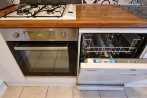 a stove and an open oven with a dishwasher at Agréable appartement avec 2 places de parking dans le garage in Béziers