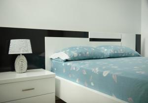 a bed with a blue comforter and a night stand at Duarte Apartments - Morabeza in Mindelo