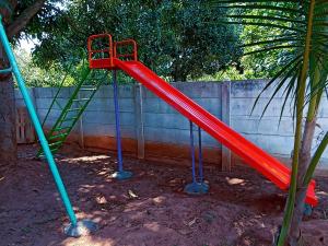 a red slide on a playground in front of a fence at Wow Farm House & Resort near Pondicherry in Auroville