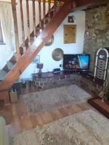 a living room with a stone fireplace and a tv at Old Coach House in Matlock