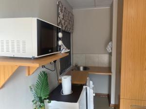 a small kitchen with a microwave on a shelf at Straebe Stay in Bloemfontein