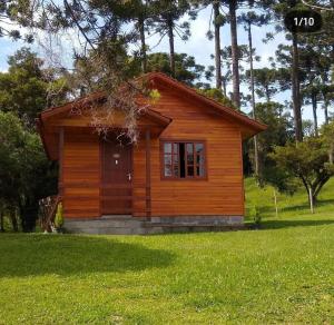 eine kleine Holzhütte auf einem Grasfeld in der Unterkunft POUSADA RECANTO DOS VAGA-LUMES in Urubici