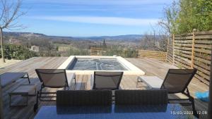 a deck with a pool with chairs and a table at Une escapade en Luberon in Bonnieux