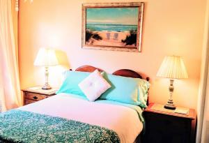 1 dormitorio con 1 cama con 2 lámparas y 1 pintura en Tropical Retreat Close to Beach, en Grover Beach