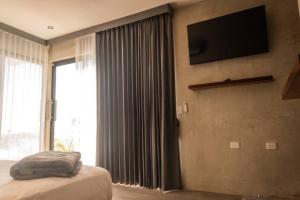 a bedroom with a bed and a television on a wall at Casa Mar Bacalar in Chetumal