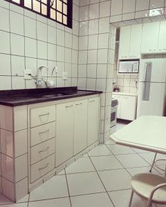 biała kuchnia ze zlewem i stołem w obiekcie Pousada & Hostel São Carlos w mieście São Carlos